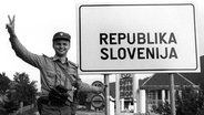 Ein Kommandant einer slowenischen Polizei Sonderheiten macht am 29. Juni 1991 neben einem Schild "Republik Slowenien" am Grenzübergang Lavamünd das Viktoria-Zeichen. © picture alliance / Gert Eggenberger / APA / picturedesk.com Foto: Gert Eggenberger