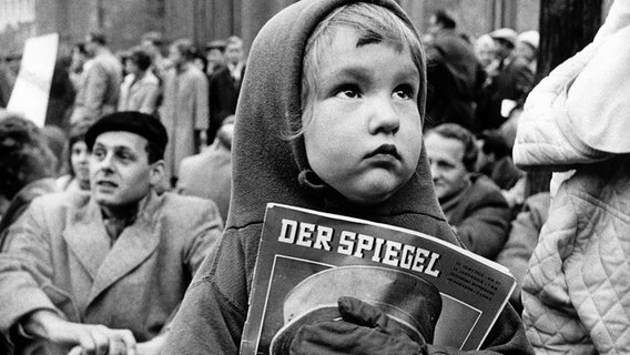 Ein kleines Mädchen hält am 30. Oktober 1962 im Rahmen einer Demonstration gegen die Verhaftung von "Spiegel"-Redakteuren eines Ausgabe des Nachrichtenmagazins in den Händen. © picture-alliance / dpa Foto: Goettert