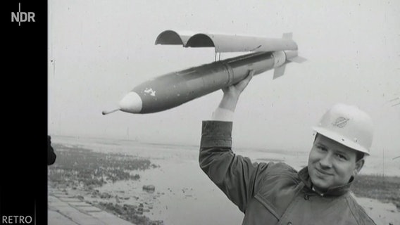 Ein Wissenschaftler hält am 23. März 1964 in Cuxhaven eine Versorgungsrekete in der Hand. © NDR 