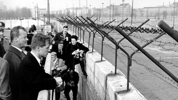 Willy Brandt und Robert F. Kennedy blicken bei dessen Besuch in West-Berlin 1962 über die Berliner Mauer. © picture-alliance / dpa 
