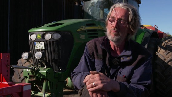 Landwirt Franz Joachim Bienstein sitzt vor einem Traktor.  