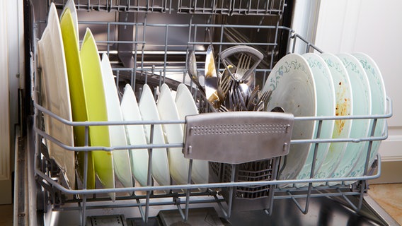 Eine Geschirrspülmaschine - im unteren Bereich stehen mehrere dreckige Teller und Geschirr © Colourbox 