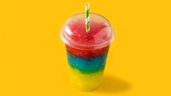 Bunter Slushie in Regenbogenfarben in einem Plastikbecher mit grün-weißen Trinkhalm. © Photocase Foto: etorres69