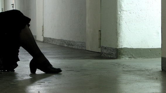 Beine einer zusammengekauerten Frau in einem Keller © photocase.de Foto: frau.L.