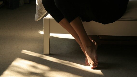 Die Beine einer auf dem Bett sitzender Frau. © photocase.de Foto: la dina