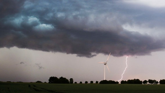 Ein Blitz schlägt neben einem Windrad in einer flachen Landschaft ein. © dpa Foto: Julian Stratenschulte