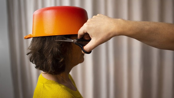 Eine Frau mit einem Topf auf dem Kopf, bekommt die Haare geschnitten. © imagi images/photothek Foto: Ute Grabowsky