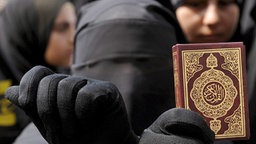 Eine vollverschleierte Muslima hält einen Koran in der Hand © dpa / picture-alliance 