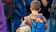 Rückenansicht eines Kindes mit Teddybär im Rucksack. © Fotoalia Foto: Lydia Geissler