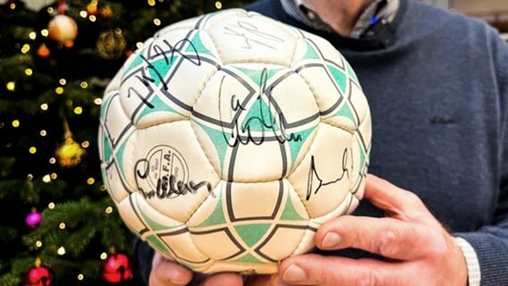Ein Mann hält einen Fußball mit Unterschriften in die Kamera. © NDR Foto: Robert Witt