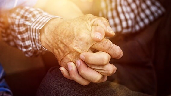Seniorenhand umfasst eine jüngere Hand. © photocase.de Foto: Brilliant Eye