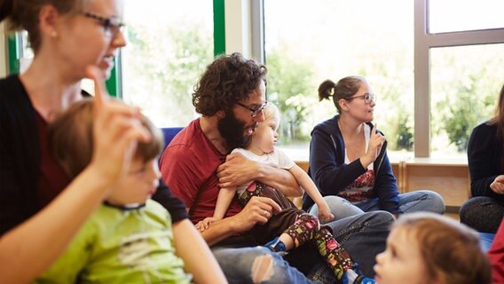 Eine Gruppe von Erwachsenen und Kindern sitzt auf dem Boden und singt. © Lebenshilfe Foto: David Maurer