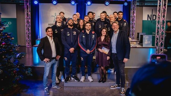 Die gut gelaunte Mannschaft der Rostock Seawolves posiert mit Eva-Maria Guhl und Clemens Paulsen für ein Gruppenbild. © NDR Foto: Katharina Kleinke