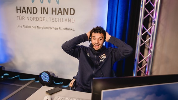Der Seawolves-Basketballer Oshane Drews am Spendentelefon ist vertieft in ein scheinbar sehr spannendes Gespräch. © NDR Foto: Katharina Kleinke