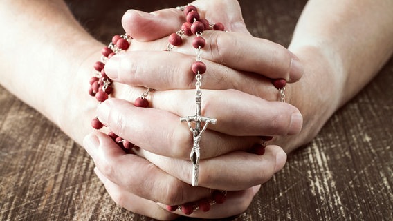 Ein Priester hält einen Rosenkranz in der Hand. © dpa Foto: Jochen Lübke