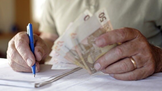 Ein Rentner macht sich Notizen und hält Euro-Geldscheine in der Hand. © picture-alliance/ dpa Foto: Andreas Gebert