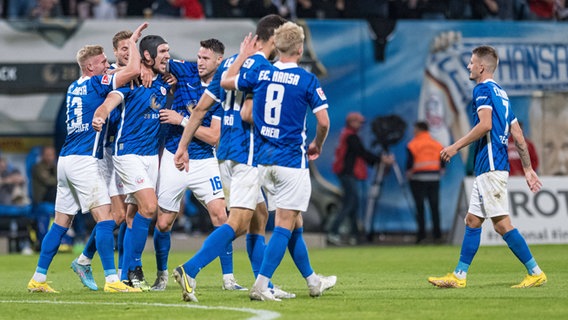 Die Spieler von Hansa Rostock feiern Matchwinner Damian Roßbach (mit Helm). © Imago/Fotostand 