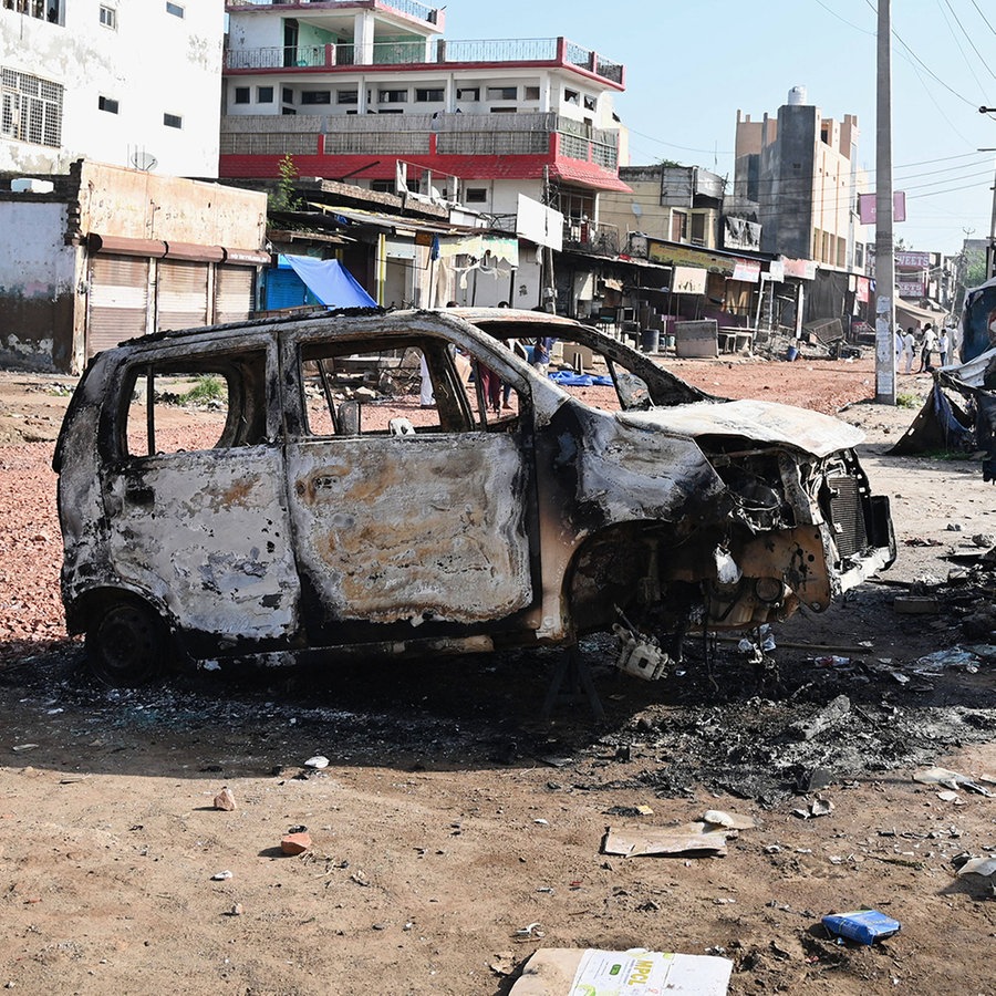 Nach den Ausschreitungen steht ein verbranntes Autos auf den Straßen © IMAGO / Hindustan Times Foto: Parveen Kumar