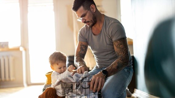 Ein Mann räumt mit einem Kind Wäsche in einen Korb ein. © Photocase Foto: Edyta Pawlowska
