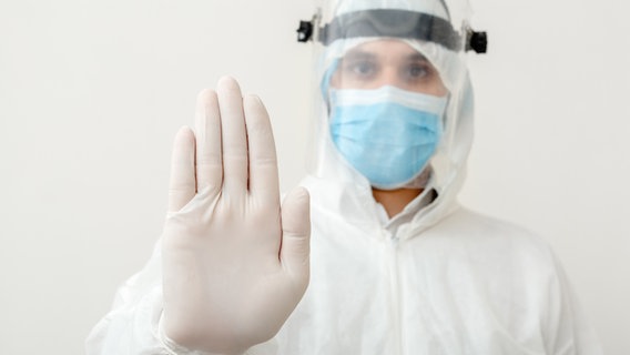 Ein Mann mit Schutzmaske, Schutzanzug und Handschuhen. © Colourbox Foto: -