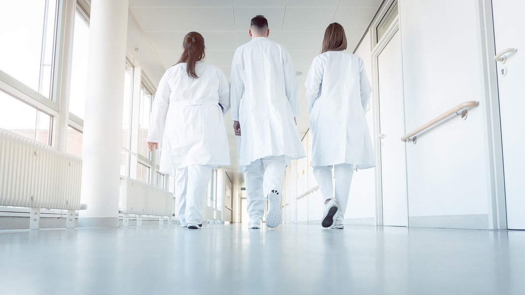 Drei Ärzte gehen einen Flur im Krankenhaus entlang 