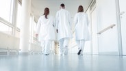 Drei Ärzte gehen einen Flur im Krankenhaus entlang © panthermedia Foto: Kzenon