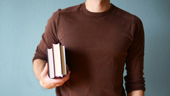 Ein Mann trägt Bücher unter dem Arm. © sör alex Foto: sör alex