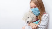 Ein Kind mit Maske kuschelt sich an einen Teddybär © Colourbox Foto: Vladimir