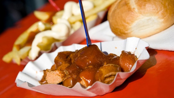 Eine Currywurst mit Pommes Frites und einem Brötchen © Colourbox 