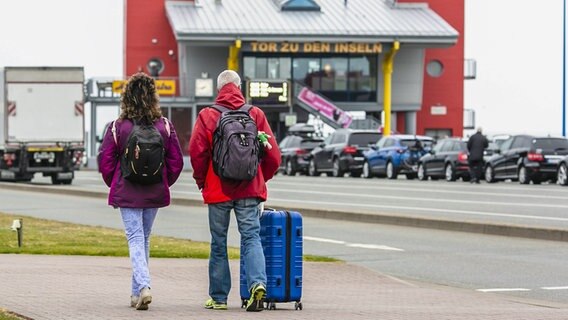 Zwei Urlauber sind auf dem Weg zum Fährterminal der Wyker Dampfschiffs-Reederei © picture alliance/dpa Foto: Frank Molter