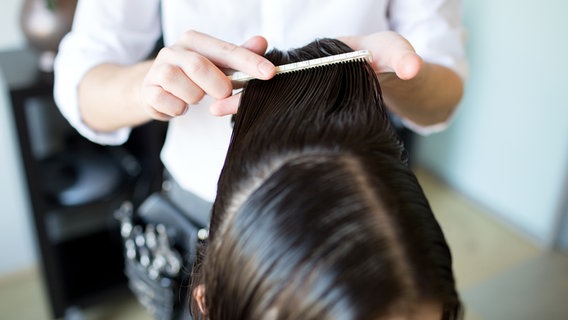 Ein Friseur kämmt die nassen Haare einer Kundin. © Colourbox Foto: Syda Productions