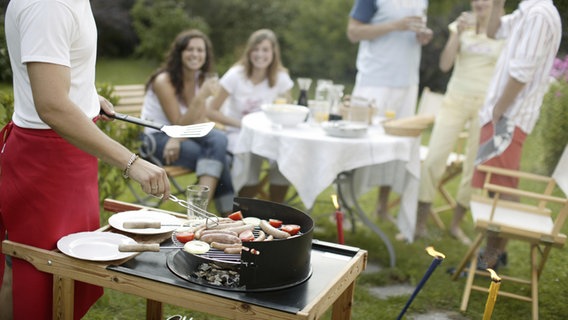 Eine Gruppe junger Menschen sitzt im Garten und grillt gemeinsam. © picture alliance Foto: Jiri Hubatka