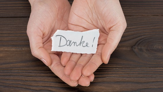 Hände halten einen Zettel mit der Aufschrift "Danke". © panthermedia Foto: VadimVasenin