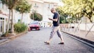 Ein Mann geht über eine Straße und blickt dabei auf sein Smartphone © phantermedia Foto: nullplus