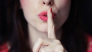 Gehobener Zeigefinger vor rotem Mund einer Frau. © photocase.de Foto: FemmeCurieuse