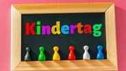 Eine Tafel mit der Aufschrift "Kindertag" in verschiedenen Farben sowie bunten Spielfiguren. © picture alliance / CHROMORANGE Foto: Michael Bihlmayer