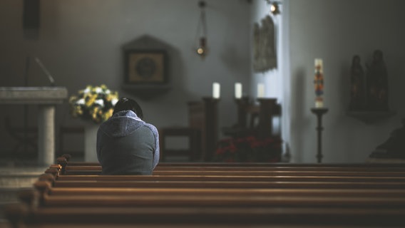 Ein Mensch sitzt betend in einer Kirche © photocase.de Foto: David W