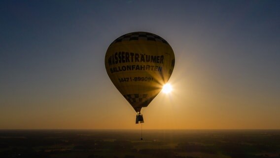 Die Band "Crackerjacks" fährt mit dem Heißluftballon vor der untergehenden Sonne über Cloppenburg und gibt ein Ballonkonzert. © dpa-Bildfunk Foto: Mohssen Assanimoghaddam/dpa