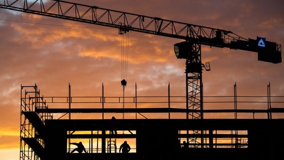 Bauarbeiter arbeiten auf einer Baustelle für ein Gebäude am Kronberg, während die Sonne aufgeht. © dpa-Bildfunk Foto: Julian Stratenschulte/dpa