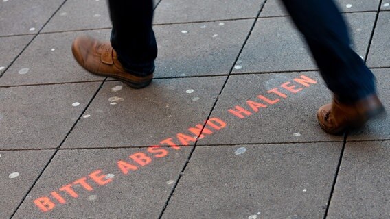 Der Schriftzug "Bitte Abstand halten" ist auf dem Boden vor dem Eingang einer Apotheke in der Innenstadt zu lesen. © dpa-Bildfunk Foto: Moritz Frankenberg/dpa