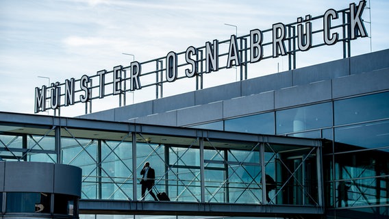 Zwei Passagiere gehen über Gangway am Flughafen Münster-Osnabrück zu ihrem Flieger. © picture alliance/dpa | Guido Kirchner Foto: Guido Kirchner