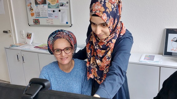 Zwei Frauen sitzen vor einem Computer und sprechen miteinander. © NDR Foto: Katrin Schwier
