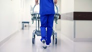 Eine Krankenschwesten schiebt ein leeres Bett auf einem Krankenhausflur. © Colourbox Foto: Syda Productions