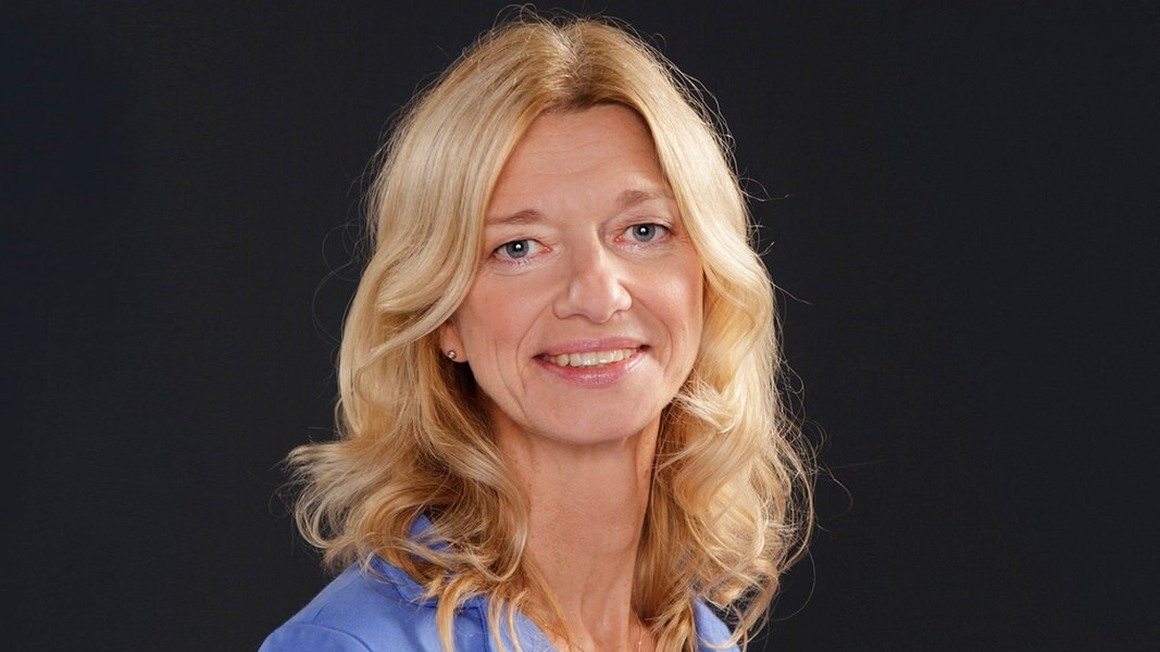 Frau mit lockigen blonden Haaren blickt freundlich in die Kamera