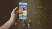 Ein Mann hält ein Smartphone, das die Dorf-Funk App zeigt. © jamie street via unsplash/ Fraunhofer IESE 