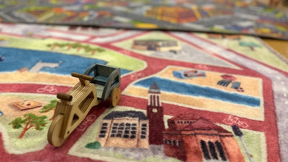 Ein Holzspielzeug steht auf einem Spielteppich. © NDR Foto: Samir Chawki