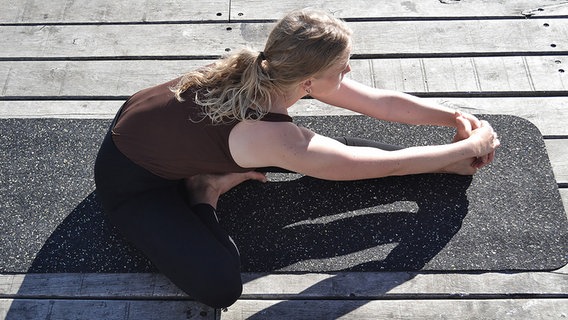 Eine Frau macht Yoga auf einer recycelten Matte. © Land and Sea 