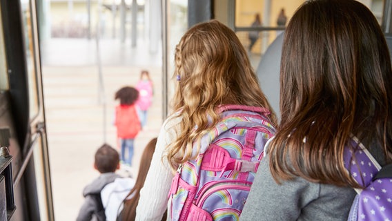 Blick von Hinten auf Kinder, die aus einem Schulbus aussteigen. © Colourbox Foto: -