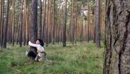 Eine Frau umarmt im Wald sitzend einen Baum. © photocase Foto: prokop