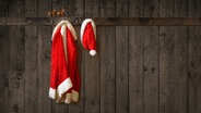 Ein Weihnachtsmann- Kostüm hängt an einer Garderobe aus Holz. © fotolia.com Foto: Springfield Gallery